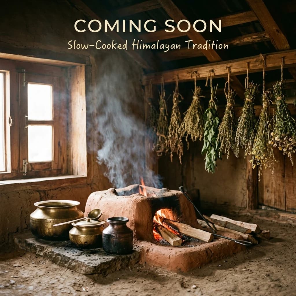 A wood fire burns in a clay hearth inside an old mud-walled Himachali house, brass pots beside it and herbs drying from the rafters